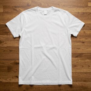 Free AI photo: White T Shirt Mockup Flat. A blank white t-shirt lies on a hardwood floor with subtle folds and shadows.. Categories: Fashion, Mockups. Colours: Gray, Orange.
